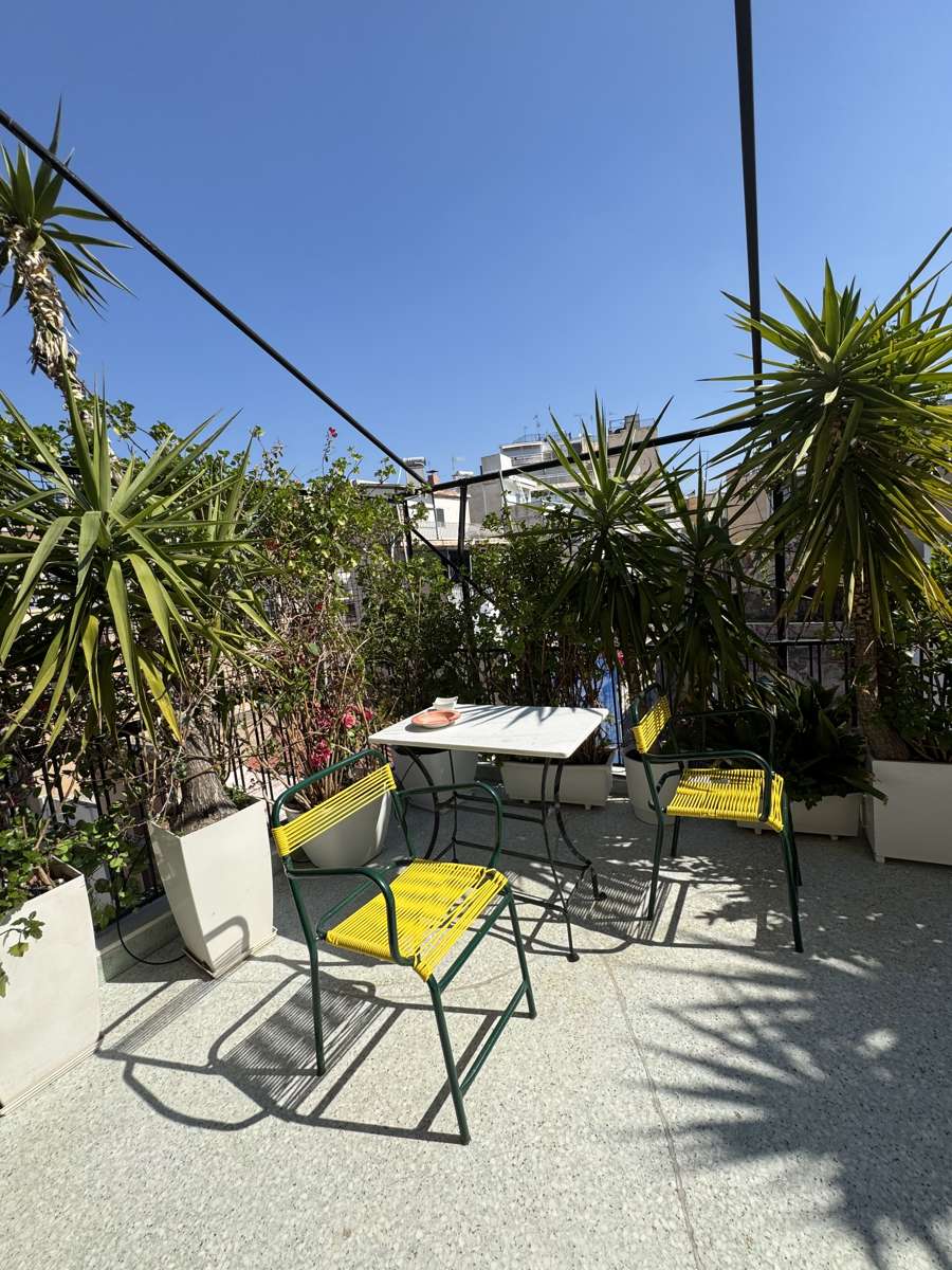 Veranda dining table with yellow chairs among plants, Monastiraki, Athens